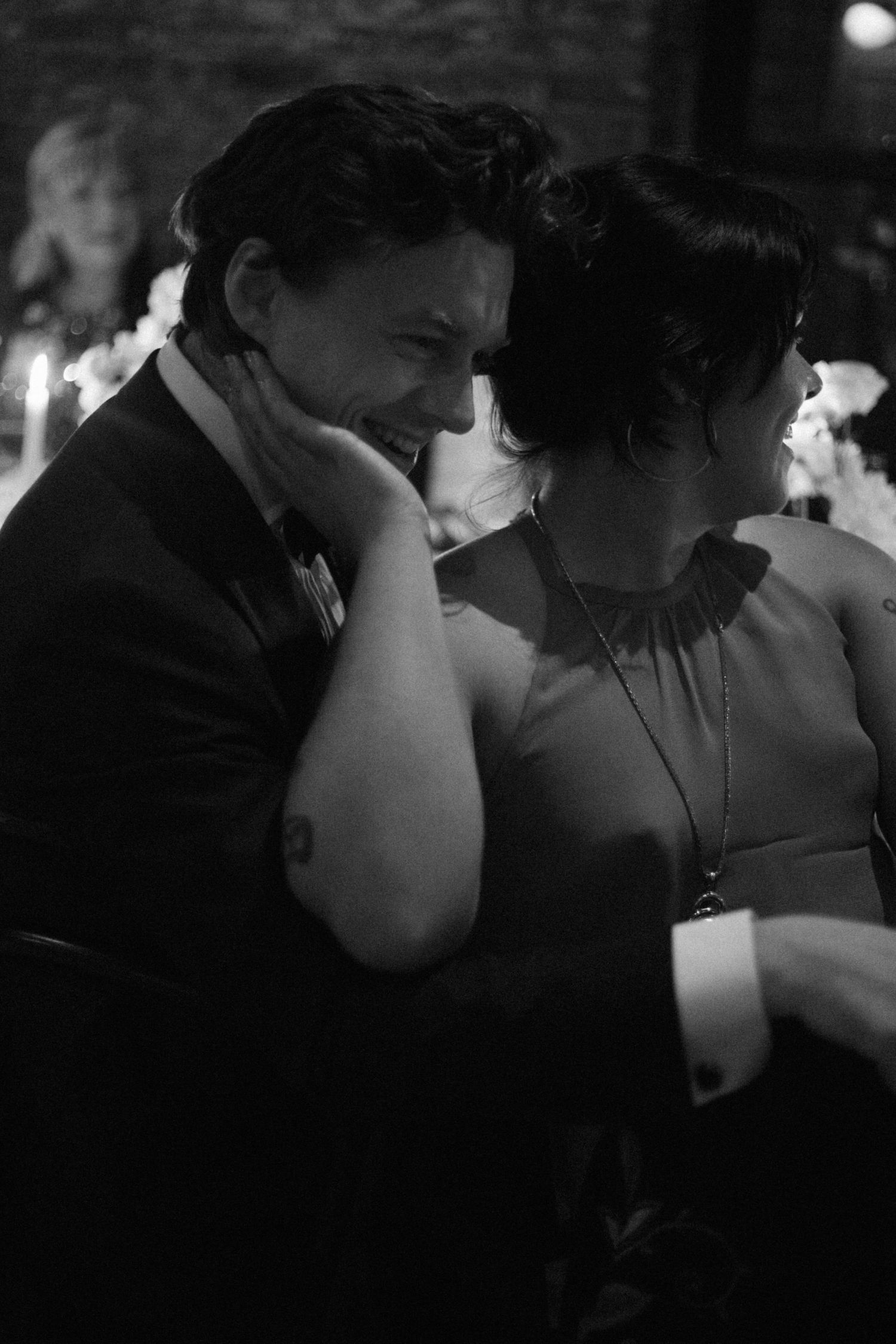 Dark and intimate reception scene with guests seated at tables in candlelight.