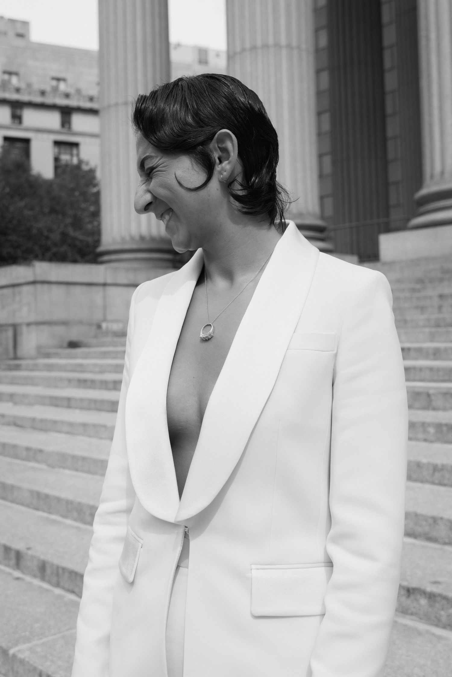 Close-up details of a white blazer with lapels against architectural columns.