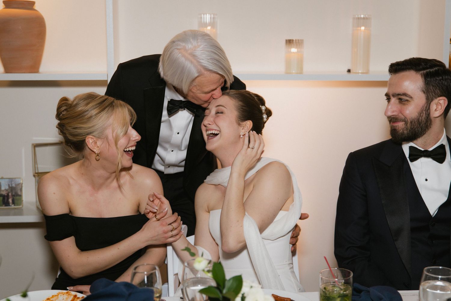Candid moment of laughter shared during an elegant wedding reception dinner.