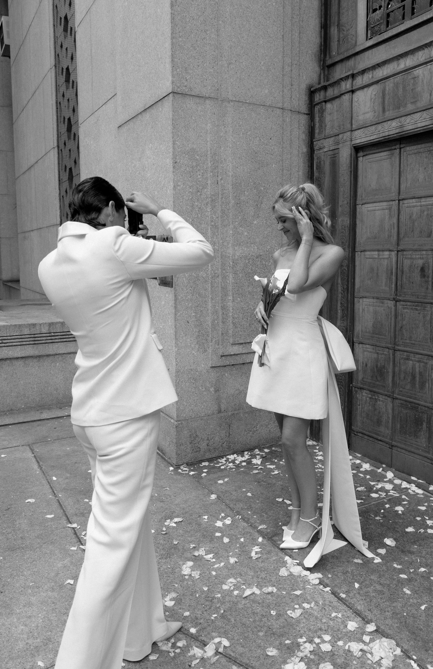 A wedding photography session in black and white with scattered petals on the ground.