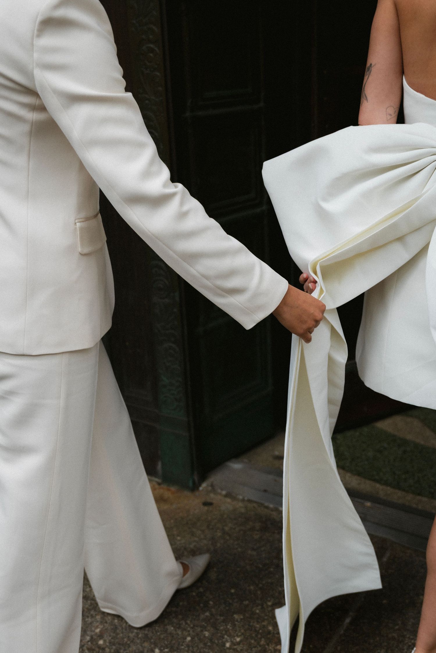 A close-up detail of white formal attire showing two people in elegant suits and dresses.
