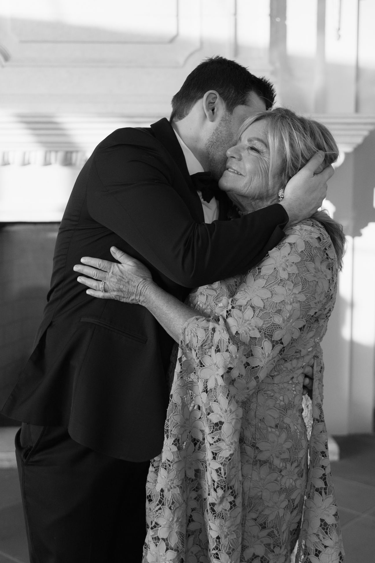 A tender black and white moment shows a warm embrace between two people during a special occasion.