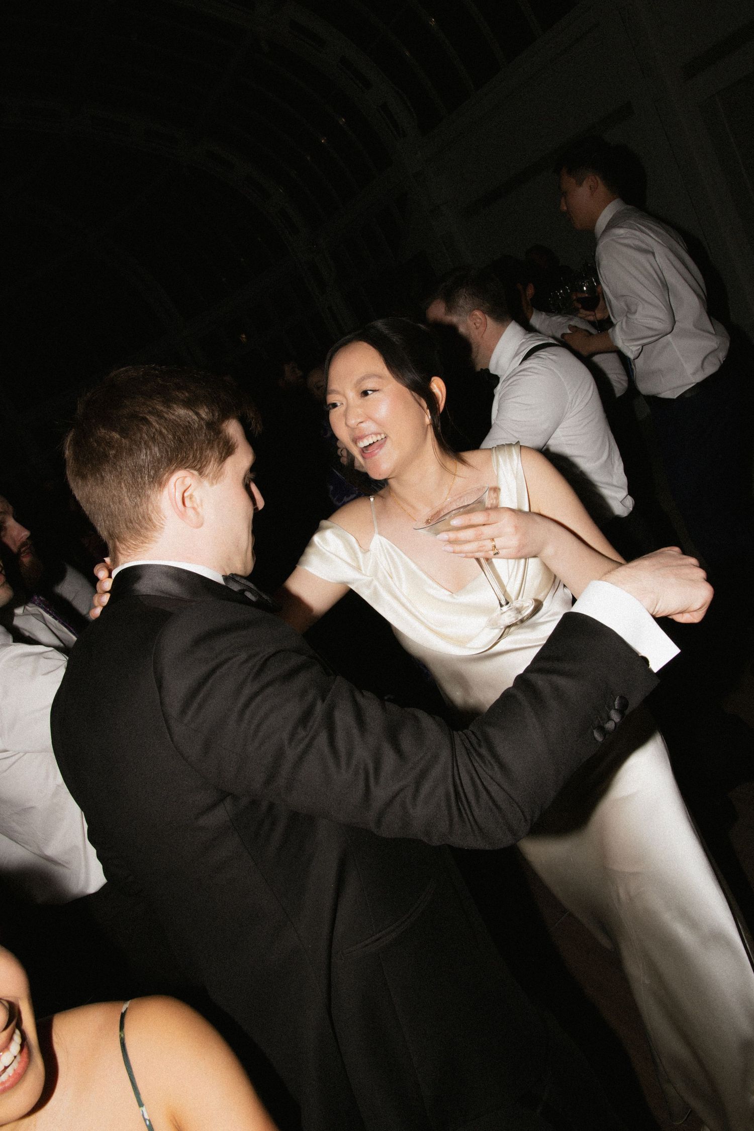 Couple dances together at wedding reception in elegant formal attire.