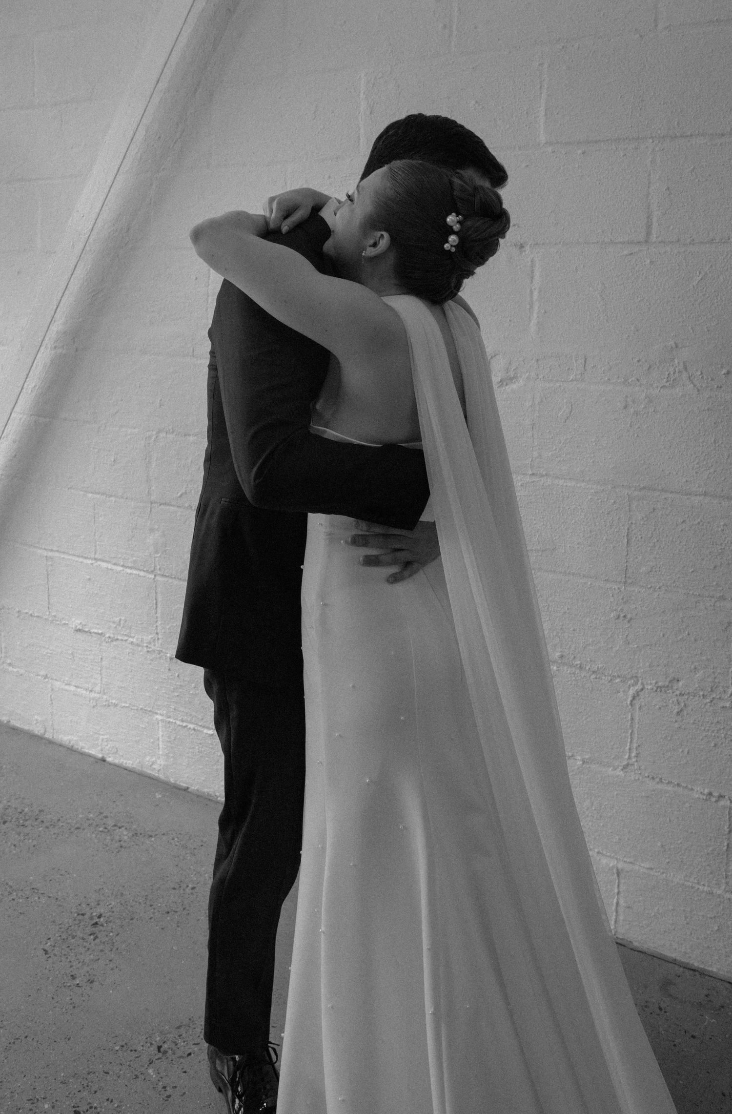A series of intimate black and white photographs showing tender embraces between a couple in a minimalist setting.
