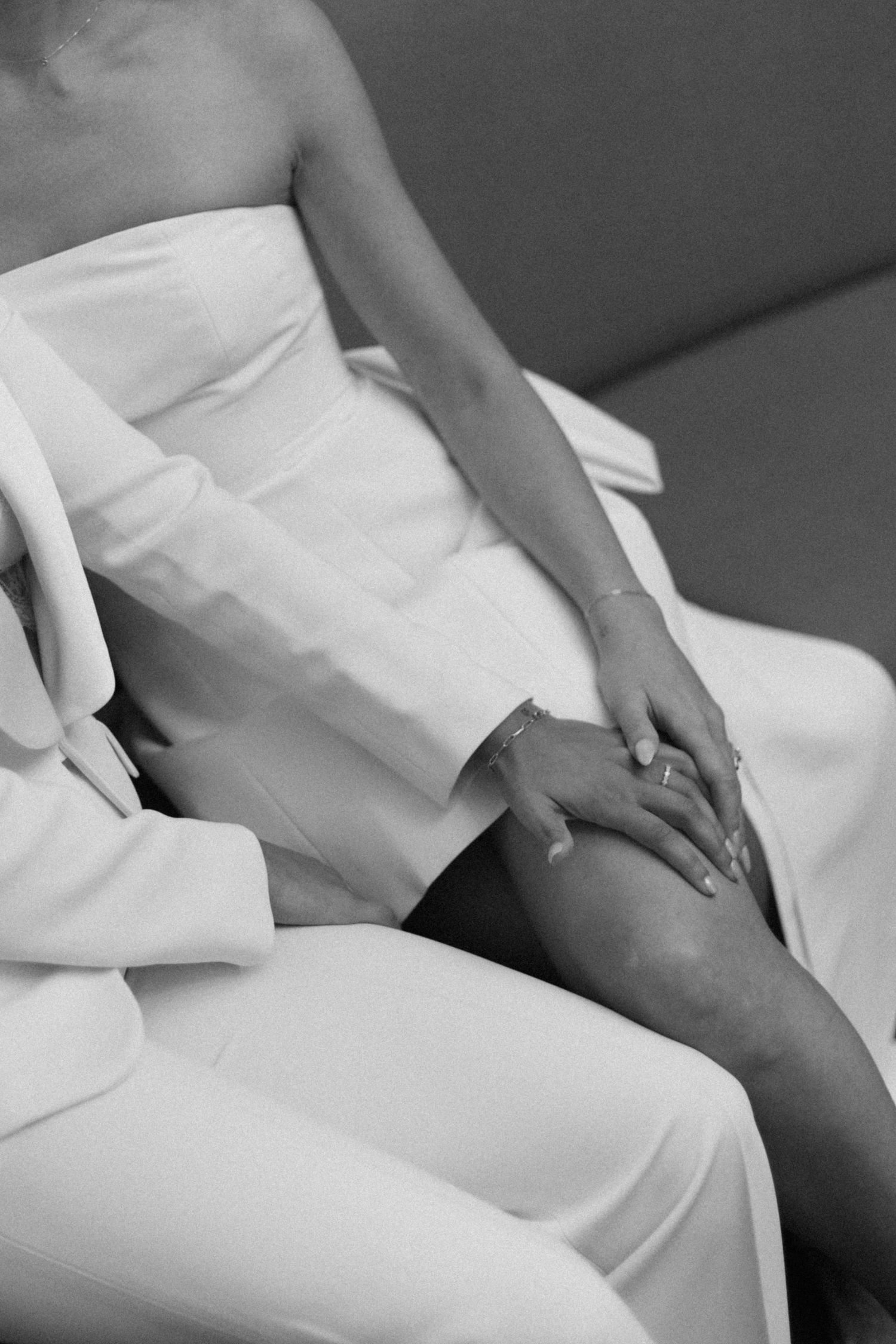 Close-up black and white image of hands resting on white fabric clothing.