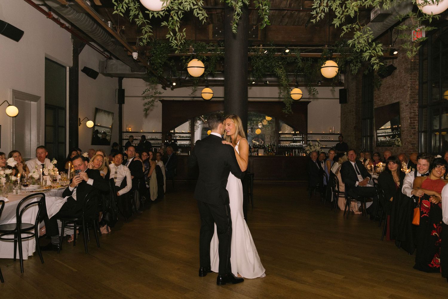Wedding reception venue with hanging lights and greenery creating a romantic ambiance for dancing and celebration.