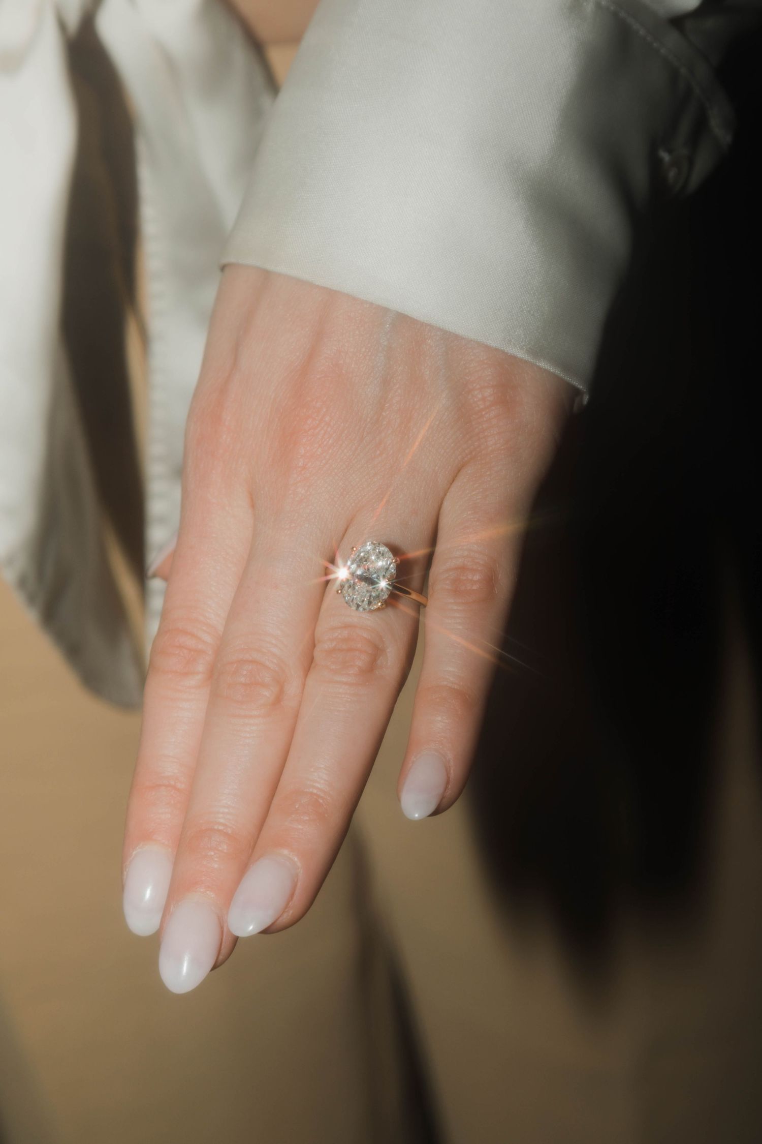 A close-up shot of an elegant engagement ring on a manicured hand.