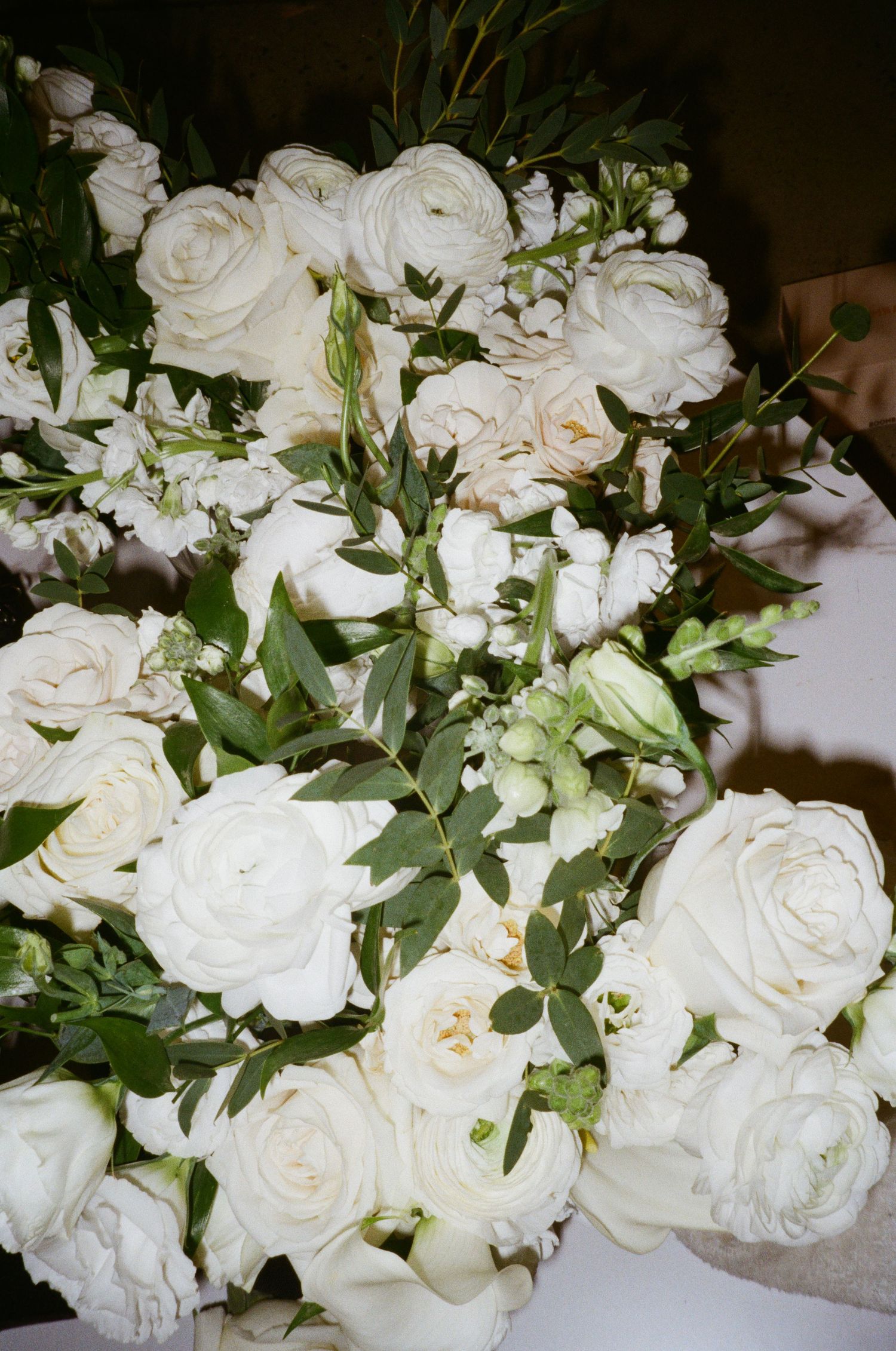 Close-up of elegant white garden roses with fresh green foliage arranged in a lush floral wedding decoration.