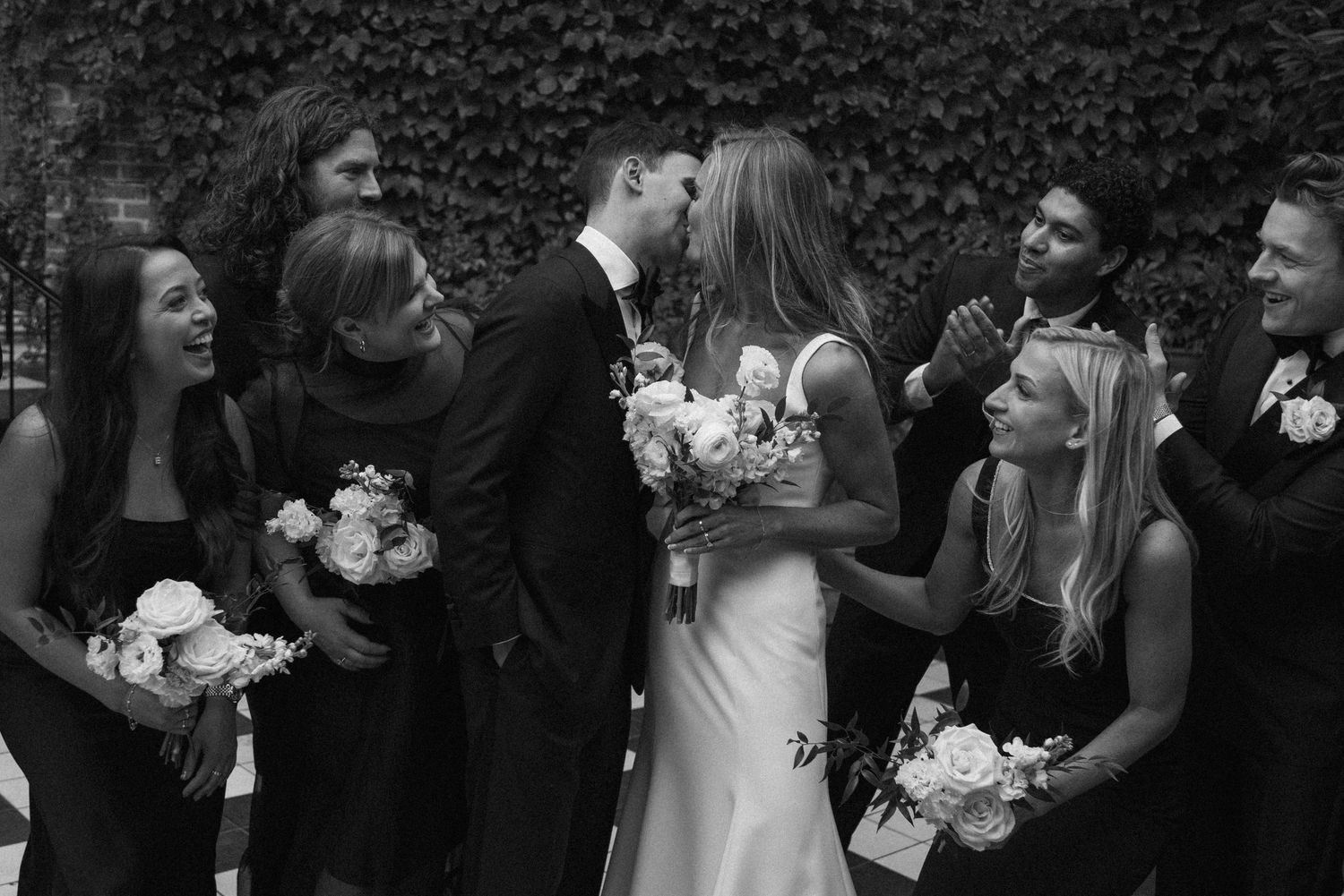 A series of black and white candid wedding photos showing joyful moments between a bride and wedding guests.