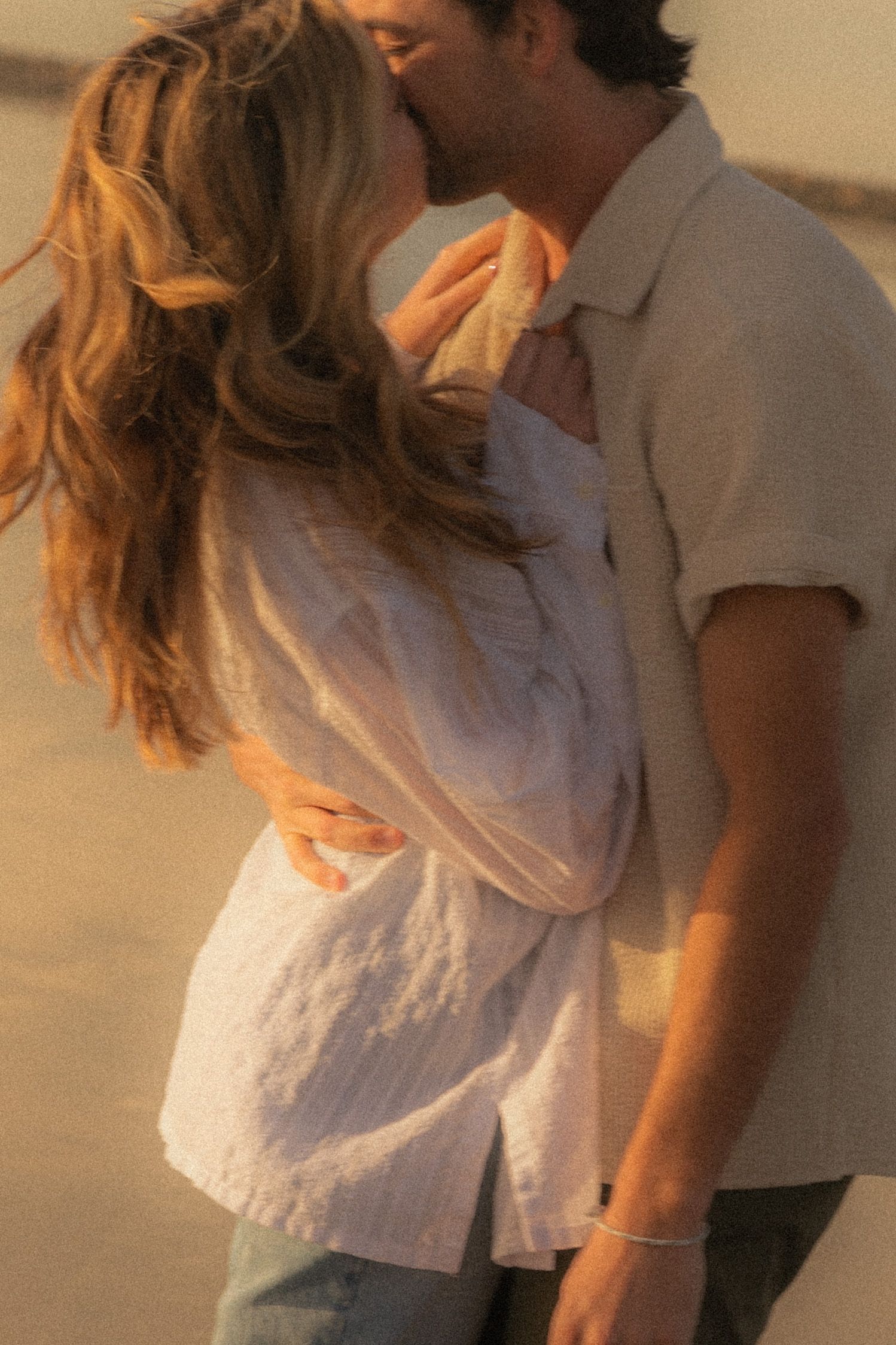 A couple embraces during a romantic golden hour photoshoot outdoors.