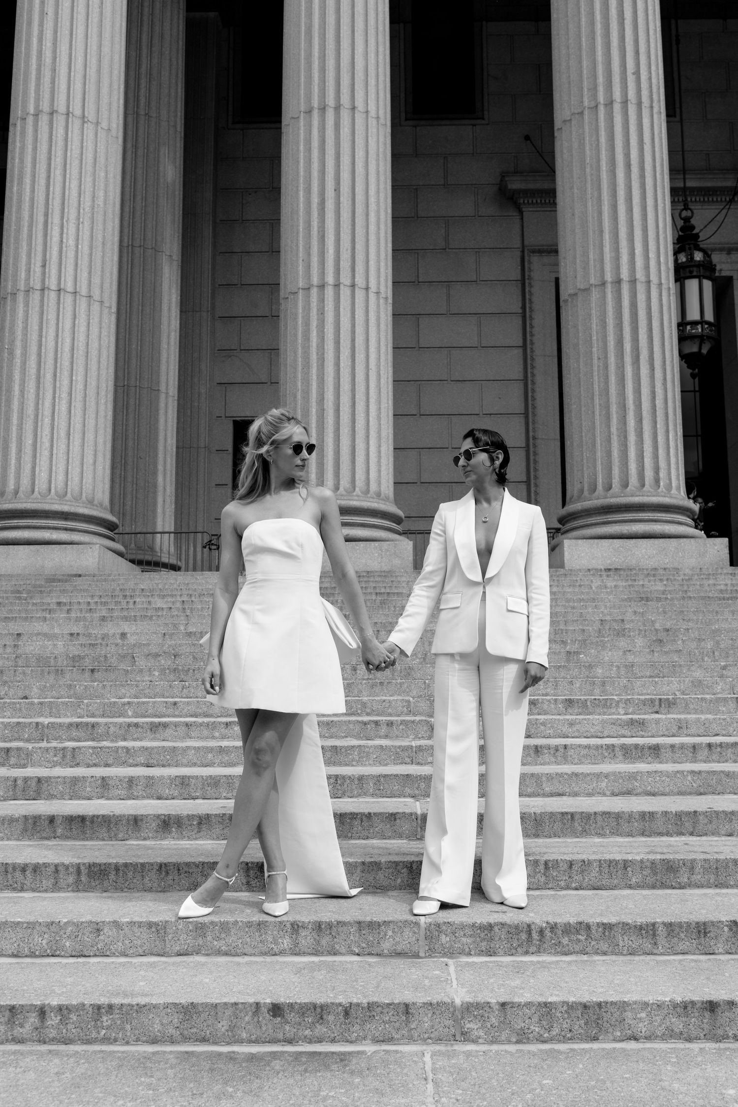 A black and white photo series showing a couple in white outfits descending stone steps with classical columns in the background.