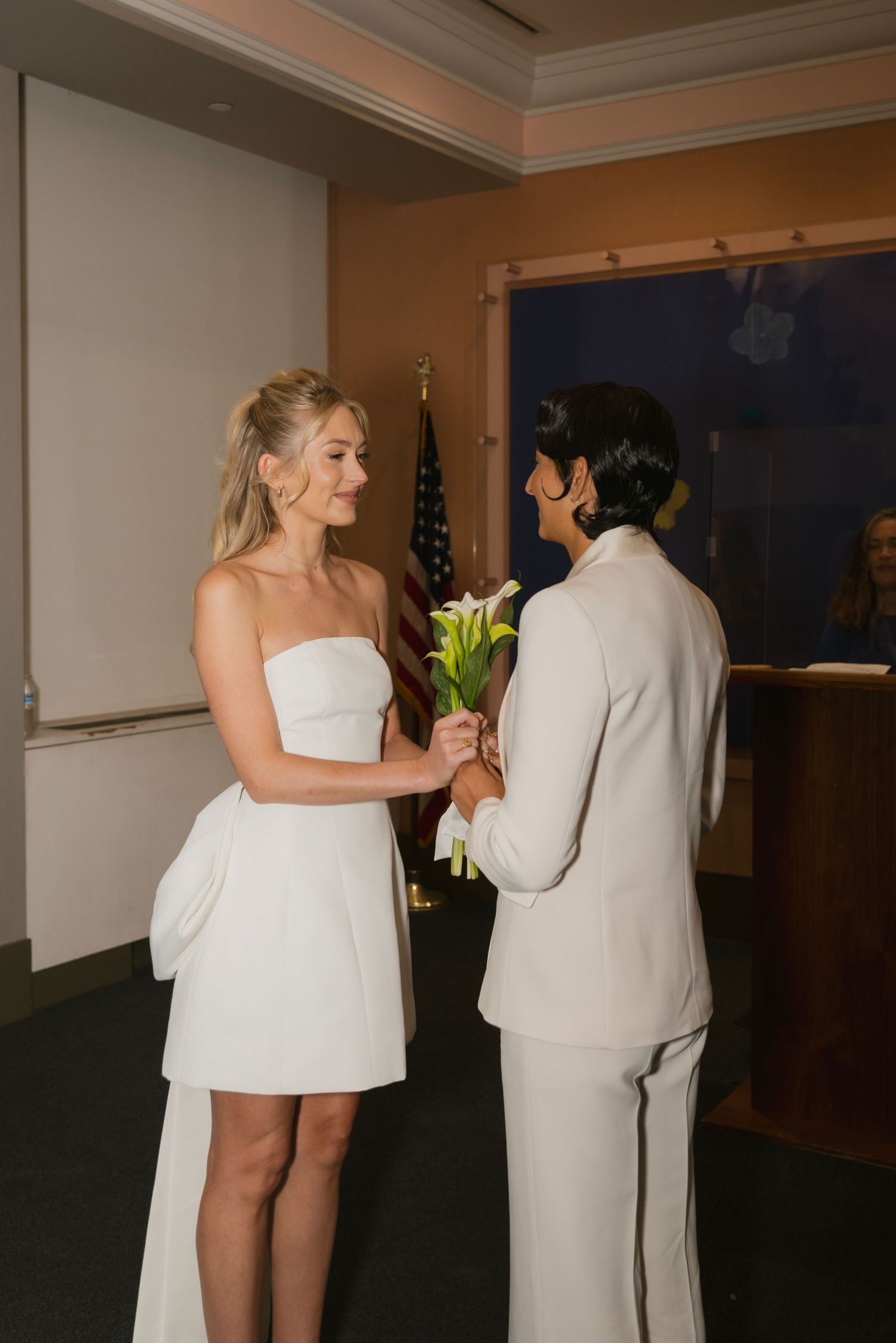 Two people in white outfits sharing an intimate moment during a wedding celebration.