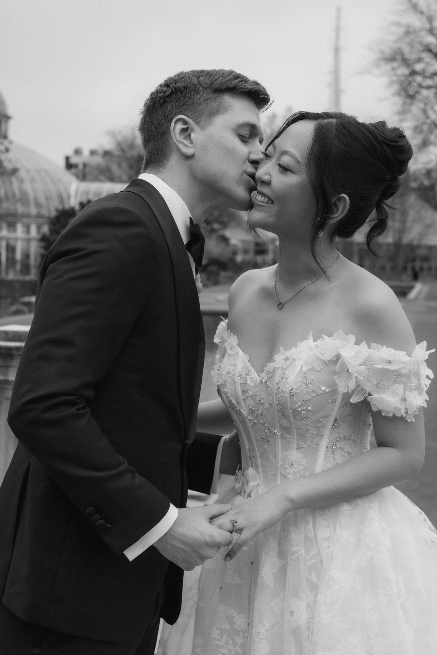 A black and white wedding photo sequence showing a romantic kiss between a couple in formal wedding attire.