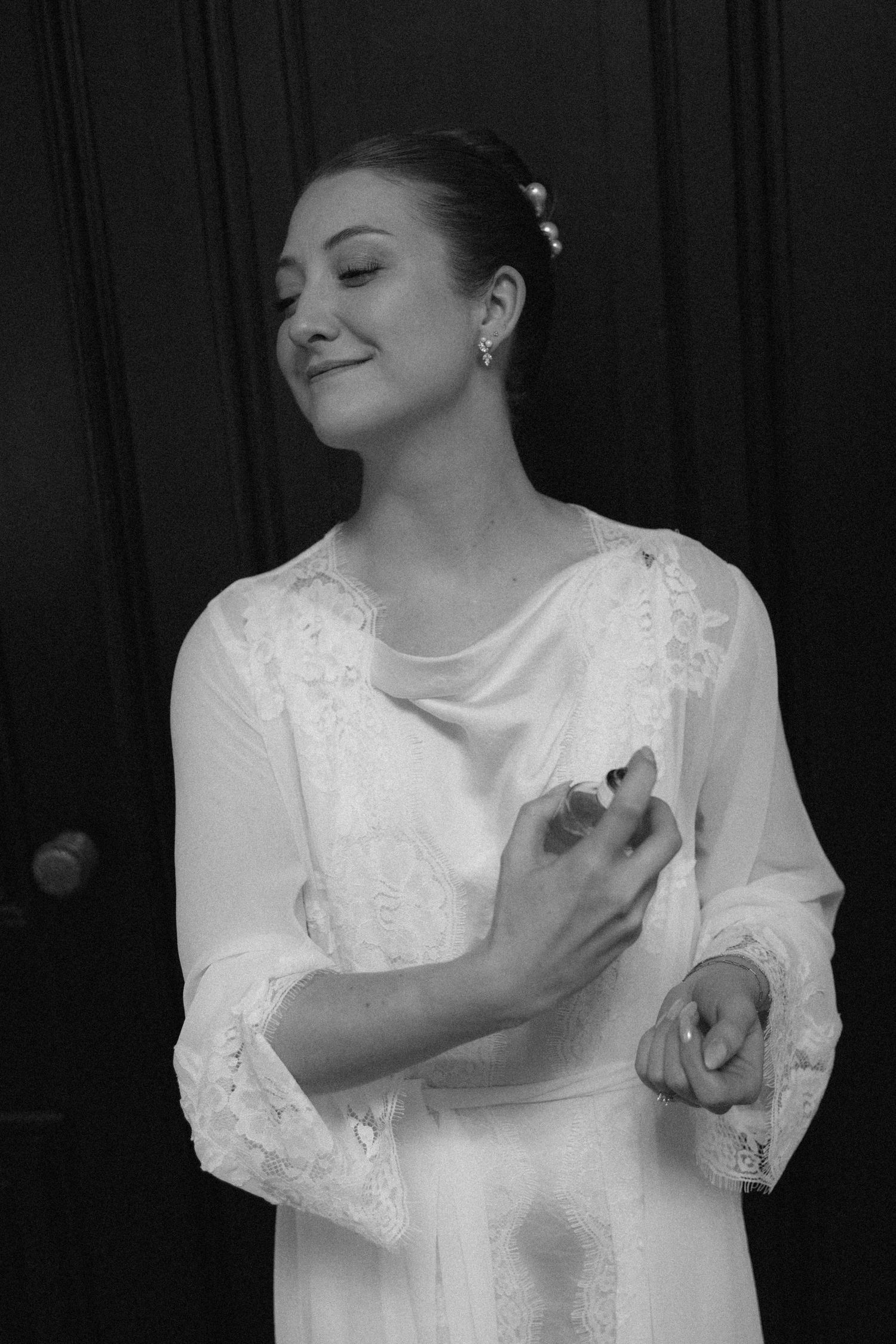 Black and white photo of someone in a lacy white dress holding a kitten with eyes closed in contentment.