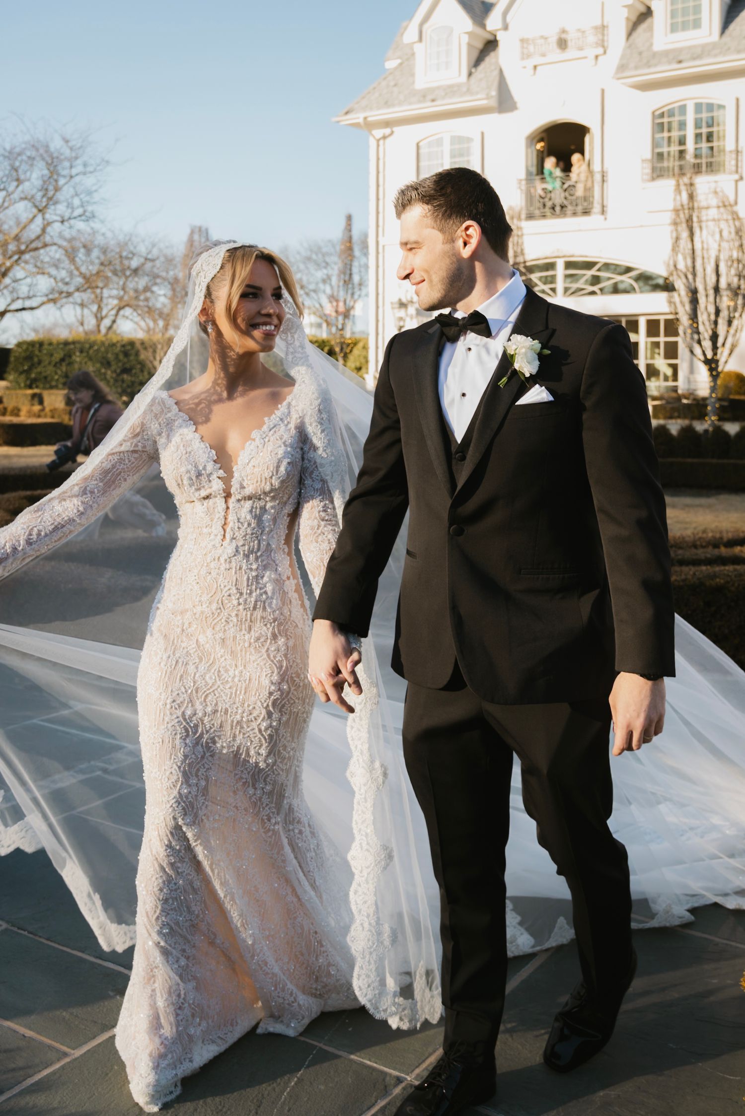 Joyful outdoor wedding photography session with a bride's veil flowing in the wind at an elegant venue.