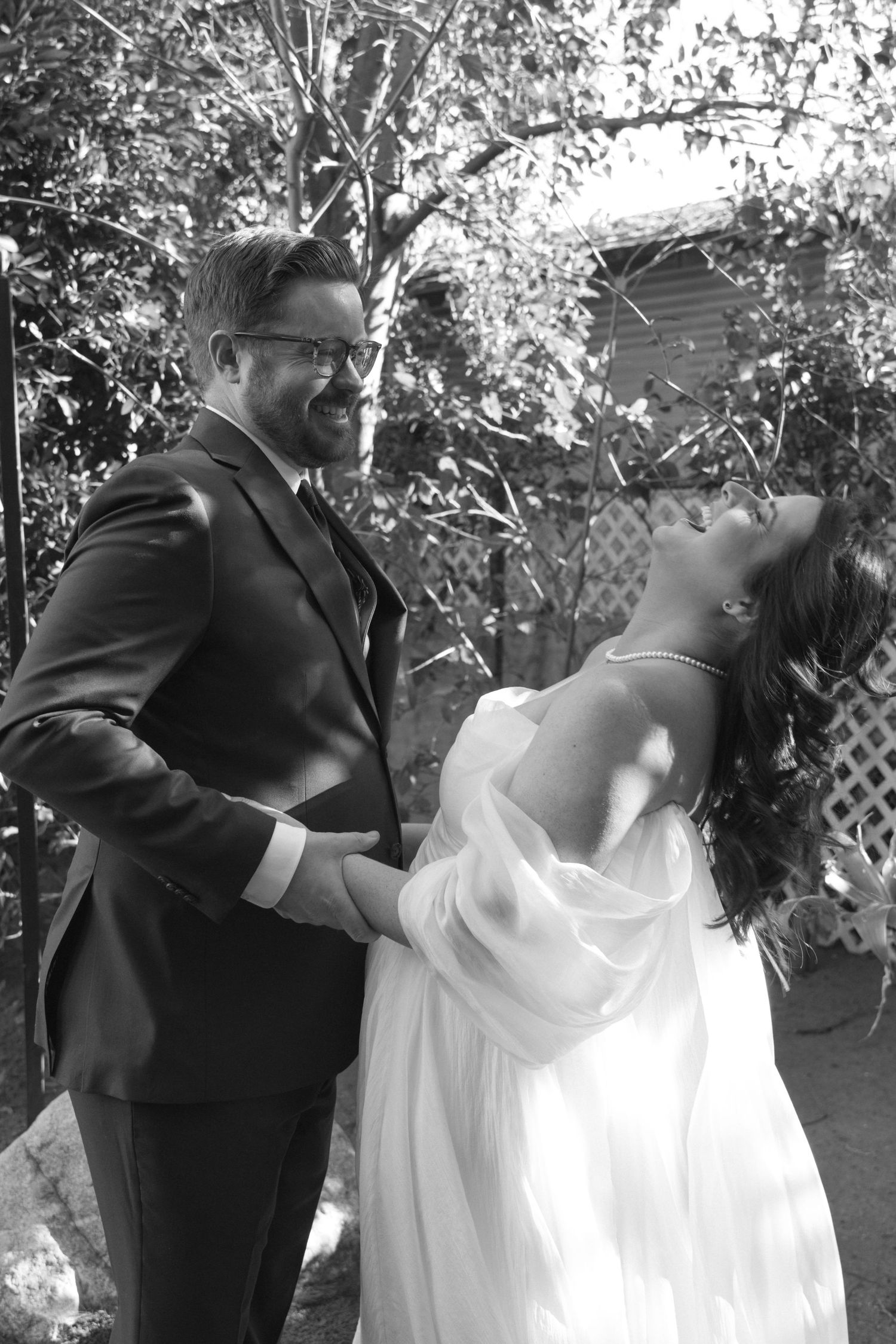 A romantic series of black and white dance poses showing a couple in formal wedding attire twirling in a garden setting.