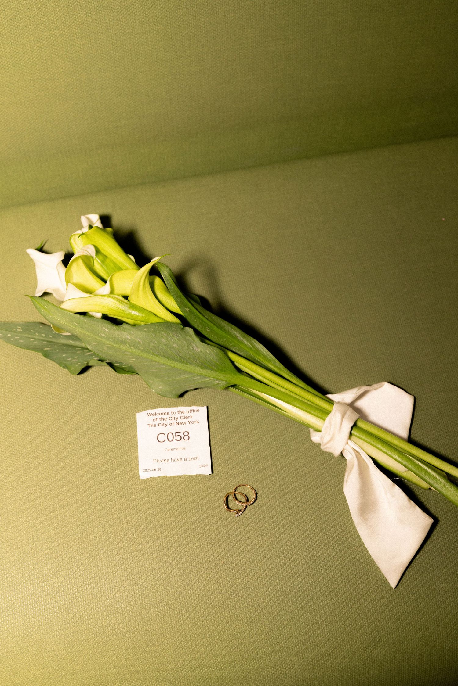A series of white lilies with green stems arranged in a gradient pattern against an olive background.