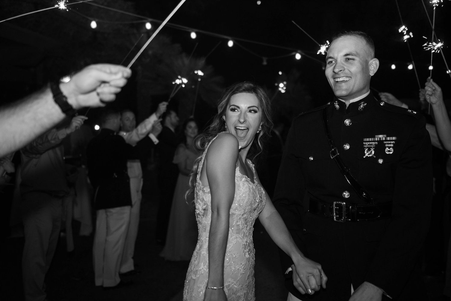 Black and white photo of bride and groom exiting through sparkler tunnel at wedding reception.