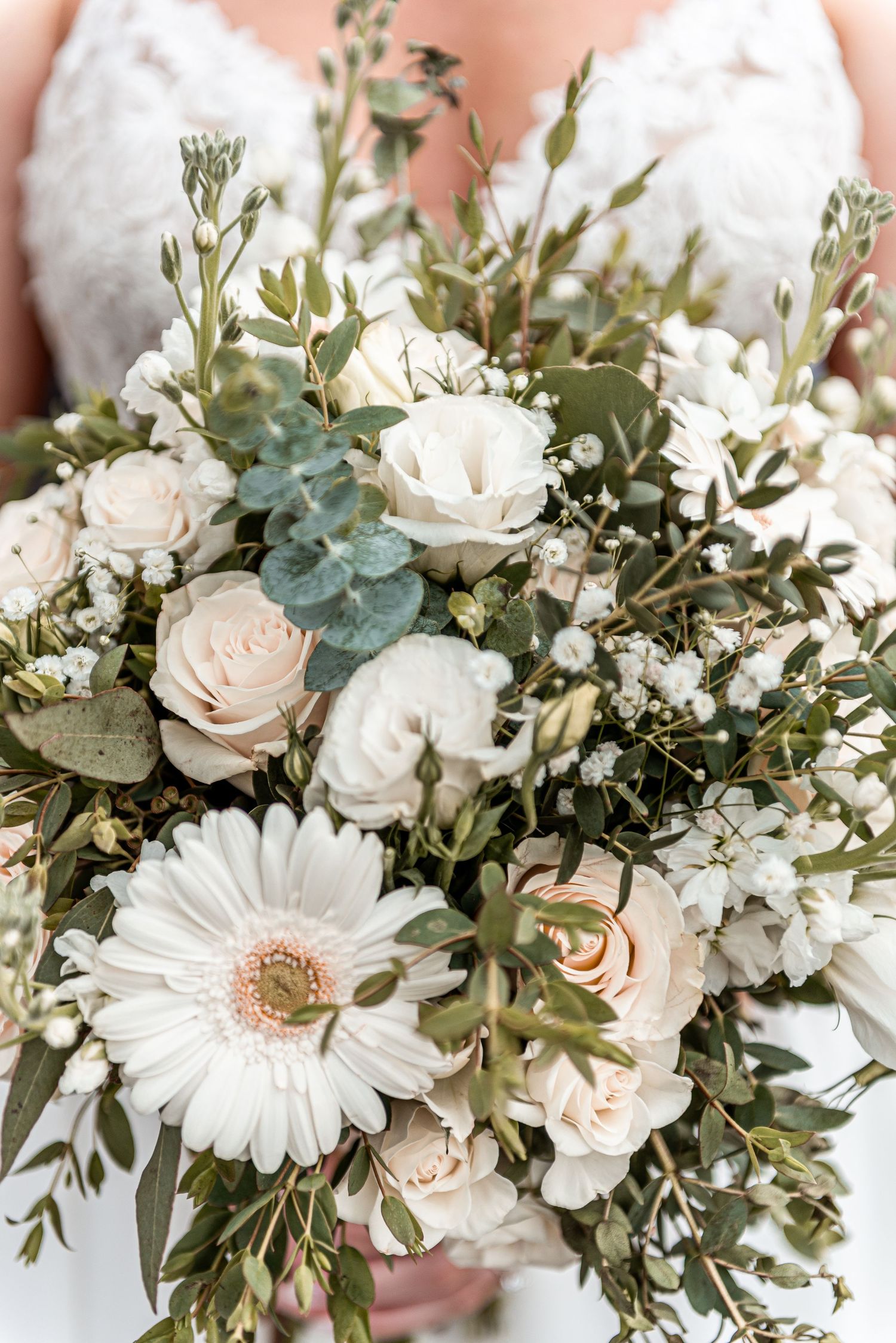Close-up of bridal bouquet with white gerbera daisies, blush roses, and eucalyptus greenery.