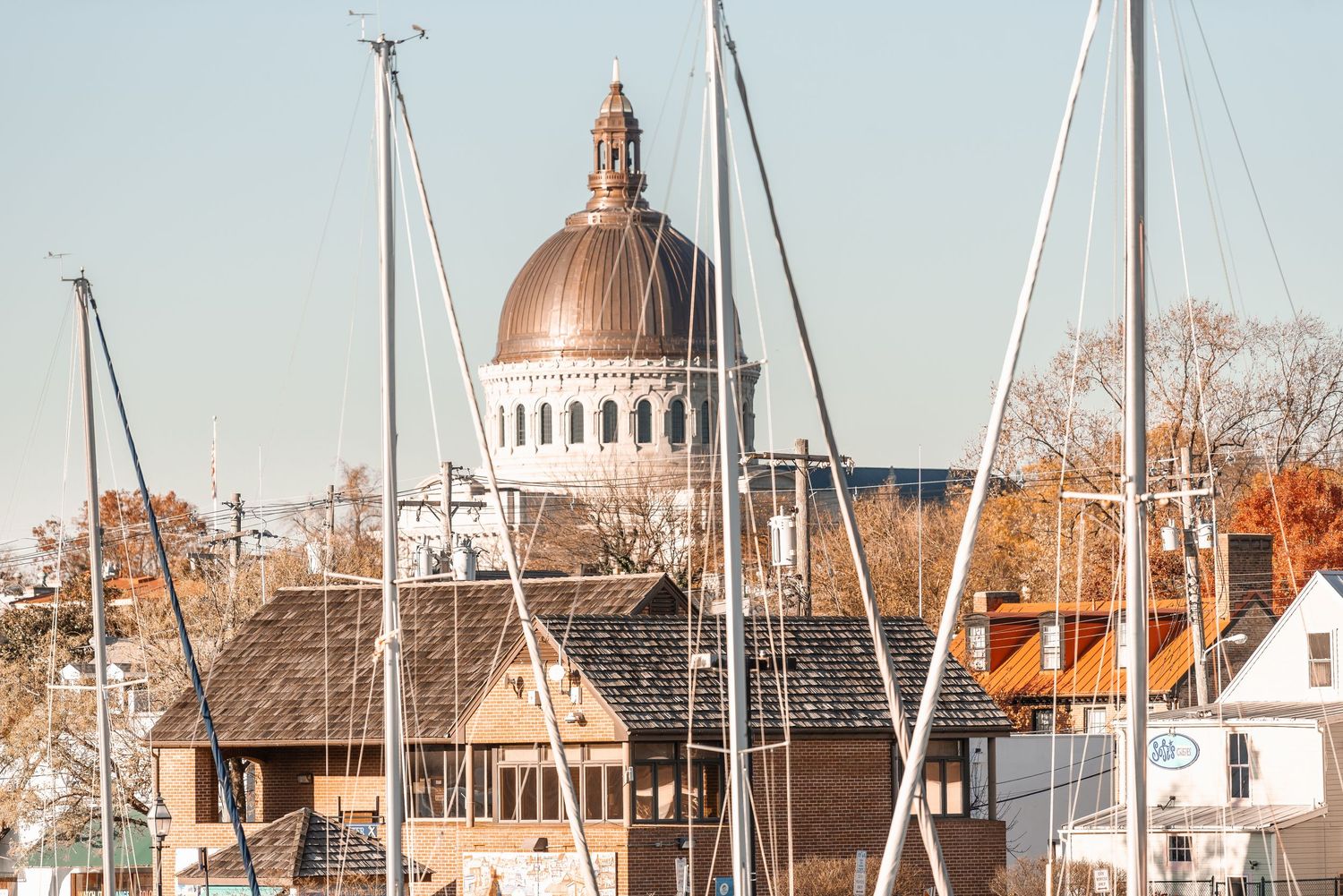 View of Naval Academy chapel copper dome rising above sailboat masts in Annapolis Maryland harbor.