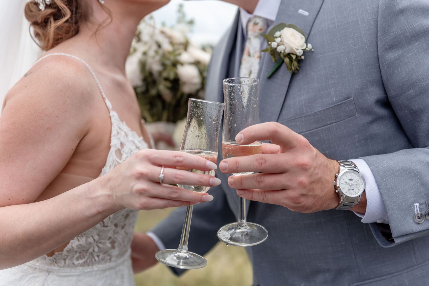 Bride and groom toasting with champagne flutes during their outdoor wedding celebration.