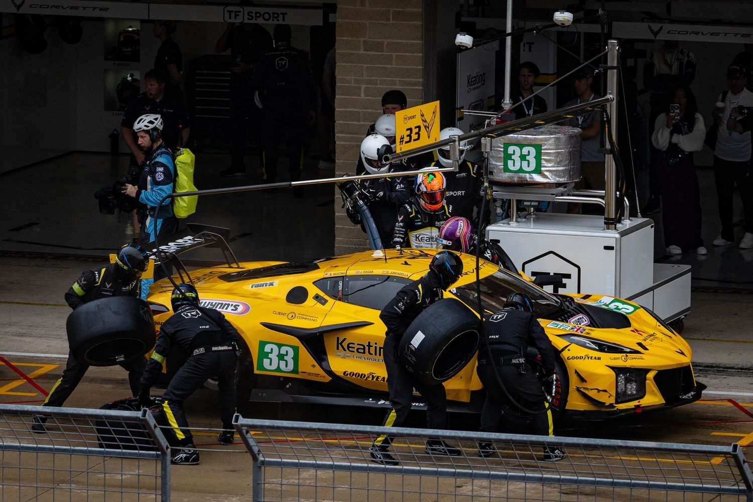 Yellow Ferrari number 33 race car during a pit stop at a motorsport endurance race.