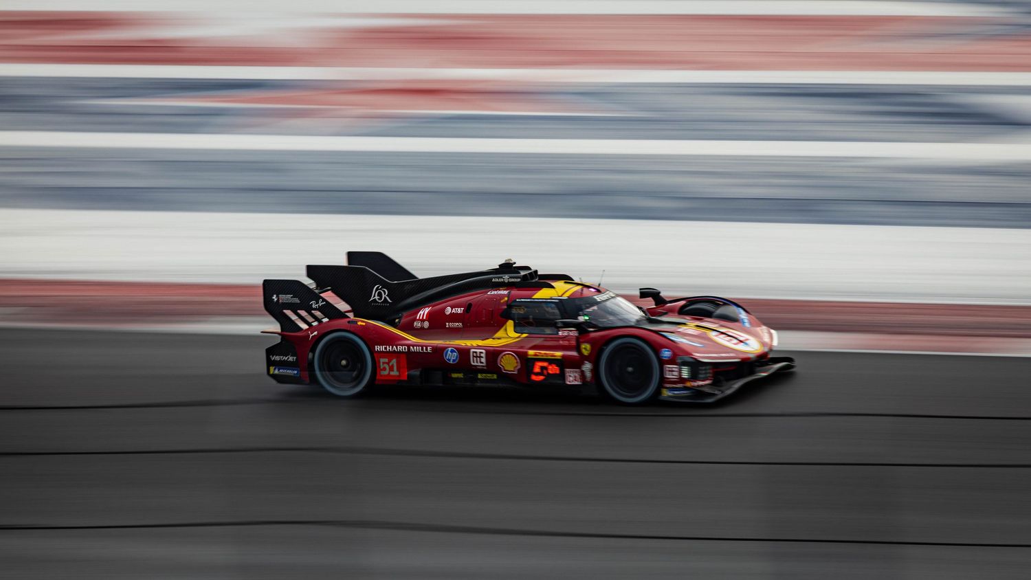 Ferrari hypercar racing at speed on track, motion blur background highlighting velocity.