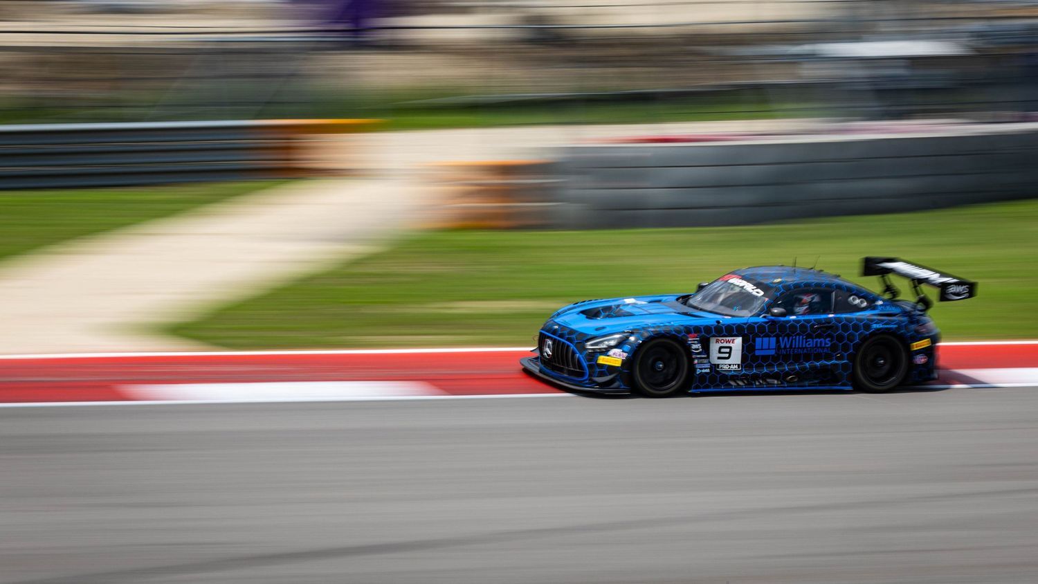 Blue Mercedes-AMG GT3 race car speeding along a circuit track with motion blur effect.