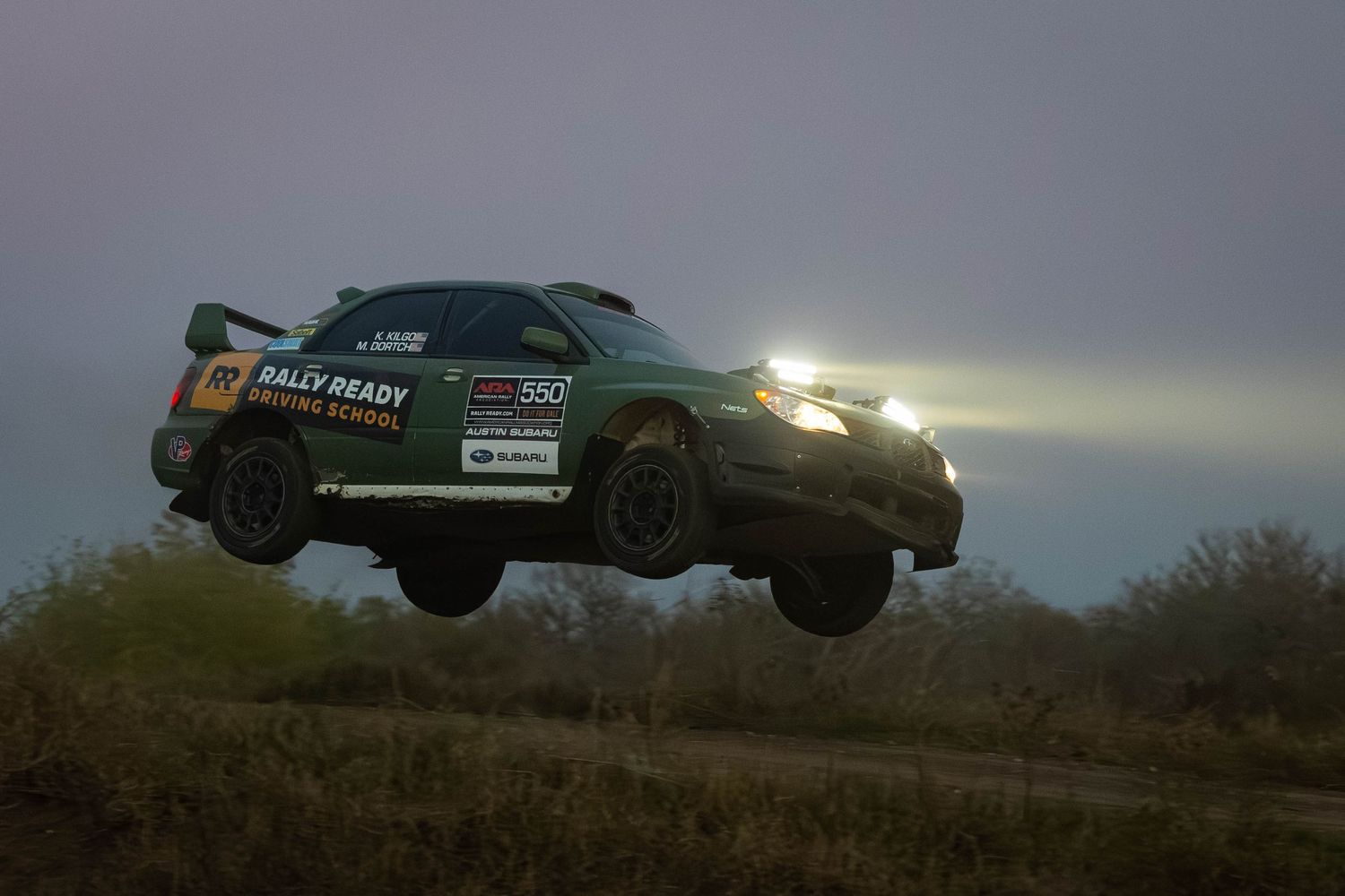 Rally Ready Subaru WRX STI catching air during a nighttime rally race stage.