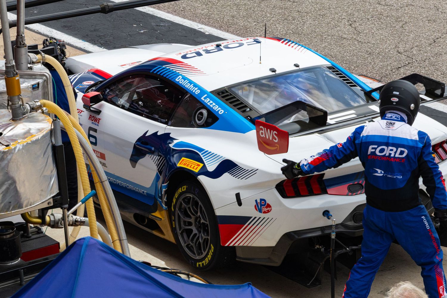 Ford Mustang GT3 race car receiving pit stop service from crew members on track.