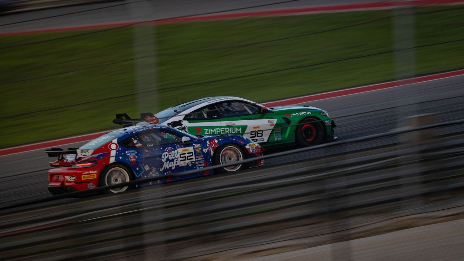Arrow McLaren IndyCar No.5 in orange livery drives past AT&T Stadium surrounded by green lawns.
