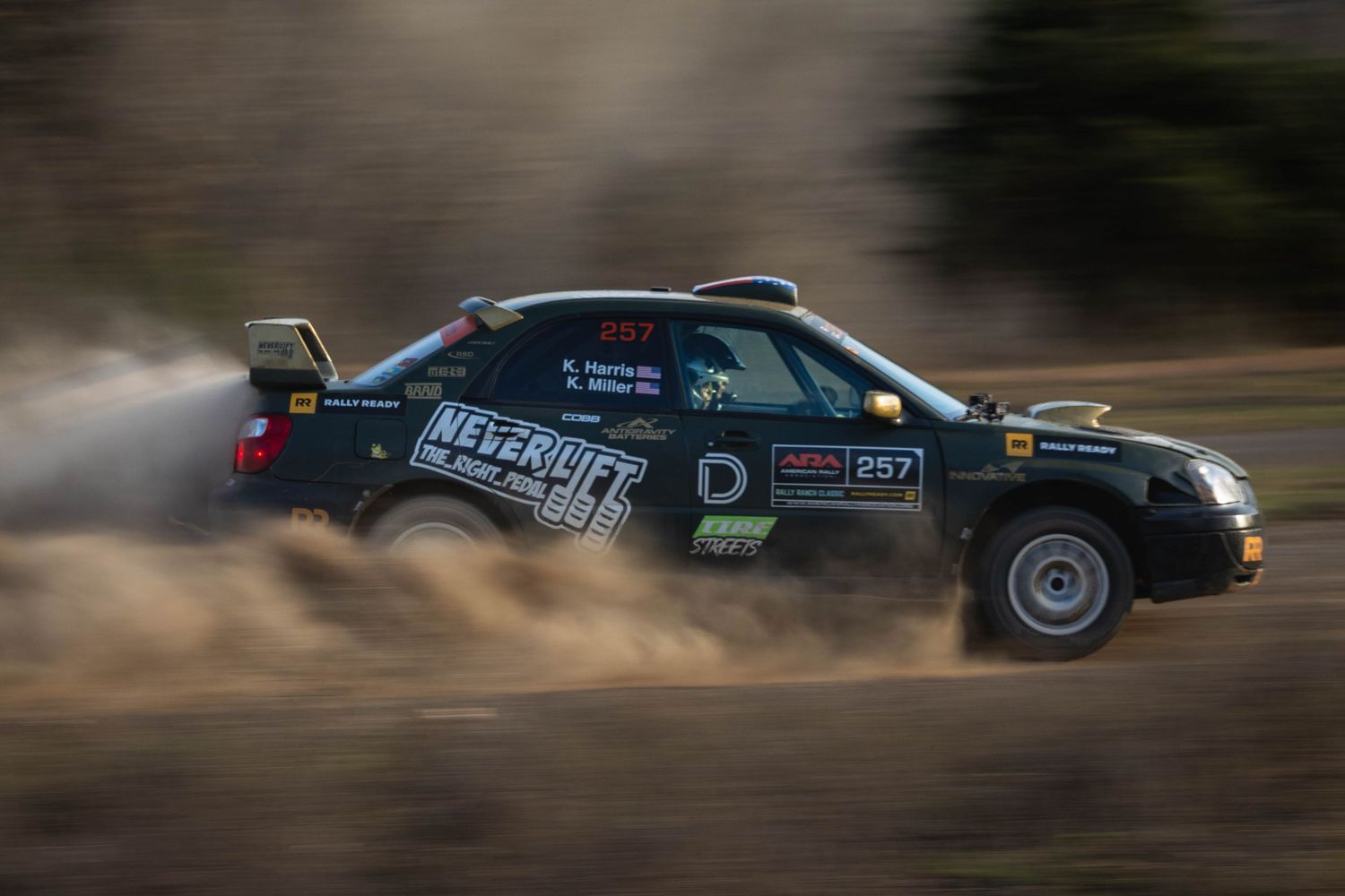 Rally car number 267 with NeverLift branding speeding through a dusty off-road rally stage.