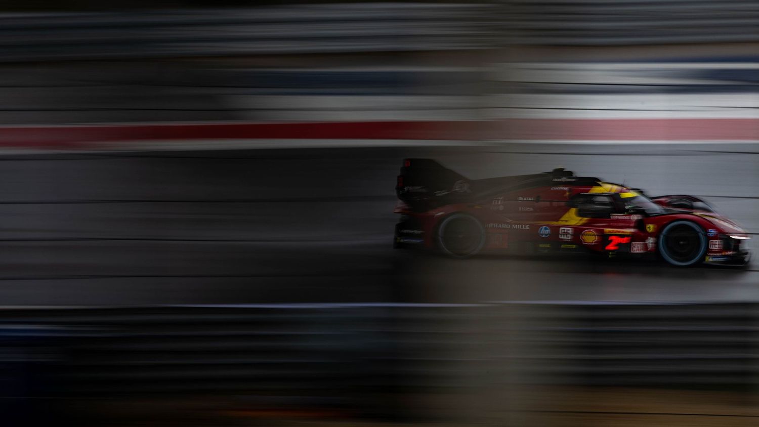Shell-sponsored GT race car captured with dramatic motion blur effect racing at night circuit.
