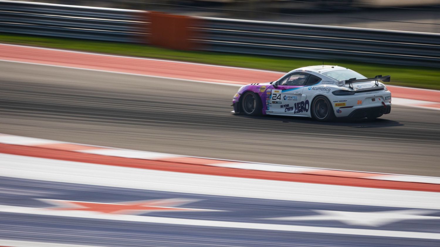 White and purple racing car speeding on a professional circuit track during a motorsport race event.