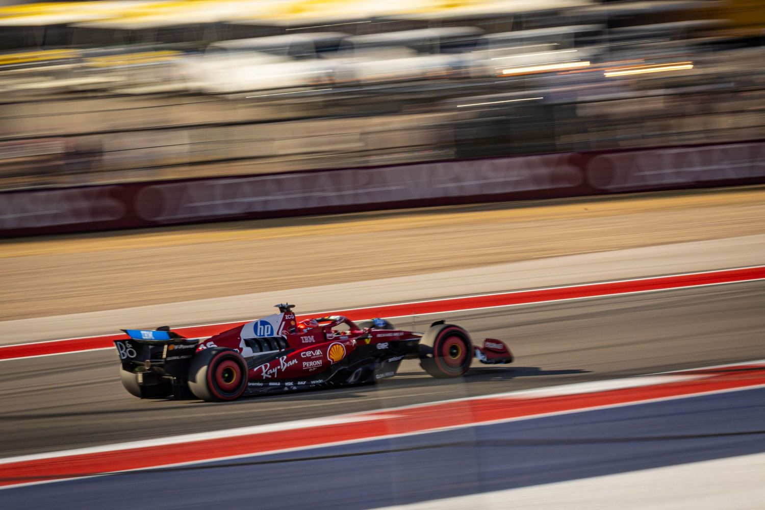 Scuderia Ferrari Formula 1 car with Lenovo sponsorship racing at high speed on a floodlit circuit.