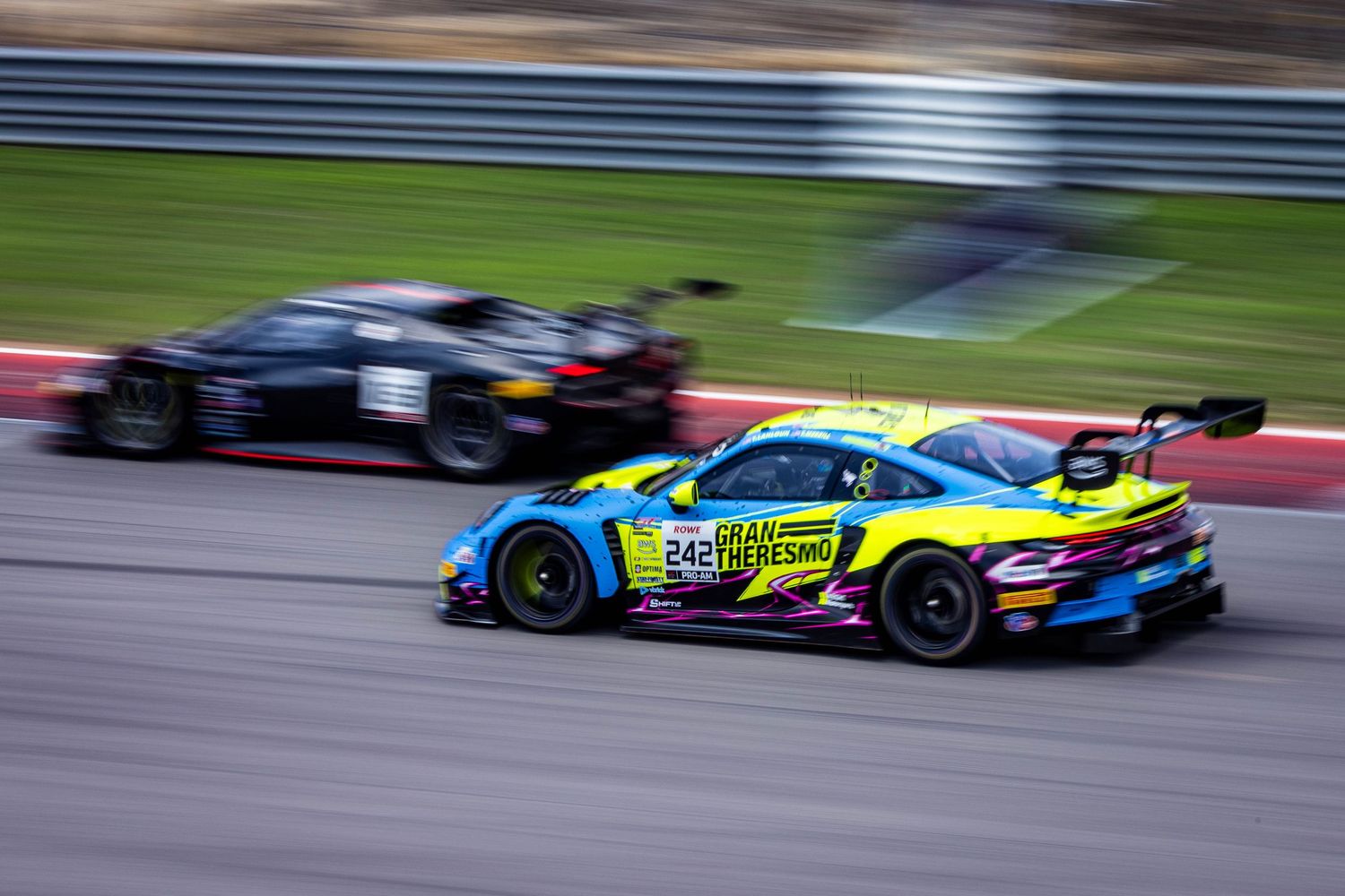 Colorful No. 24 Gran Turismo GT3 race car overtaking a black competitor on track.