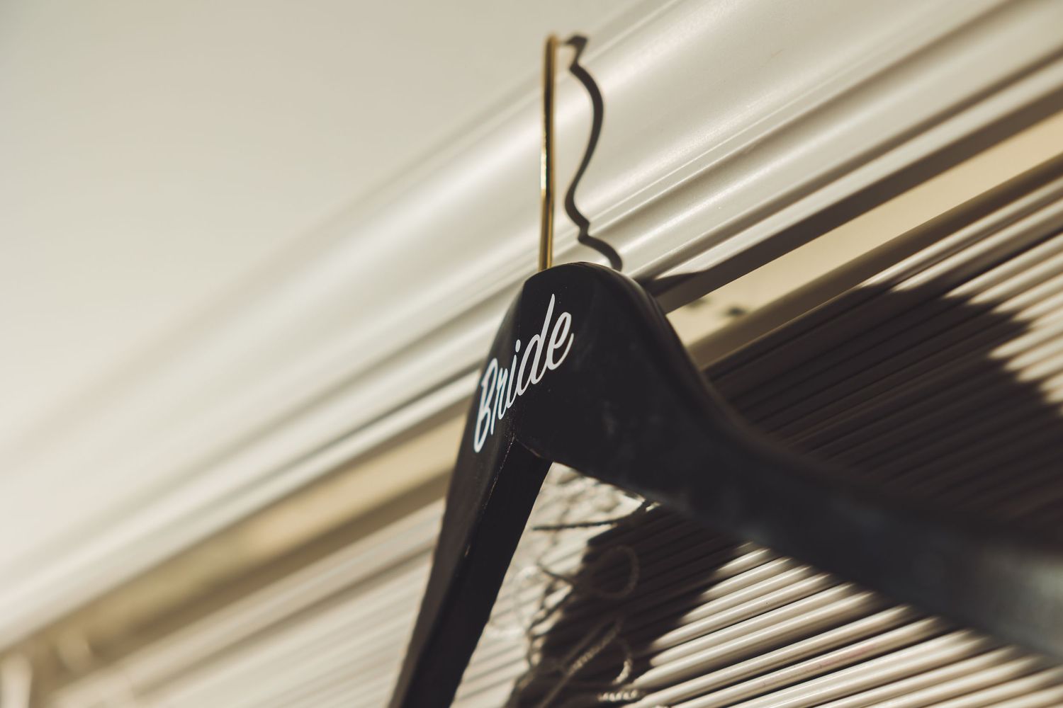 Black bride wedding hanger hanging on a curtain rod in soft natural light.