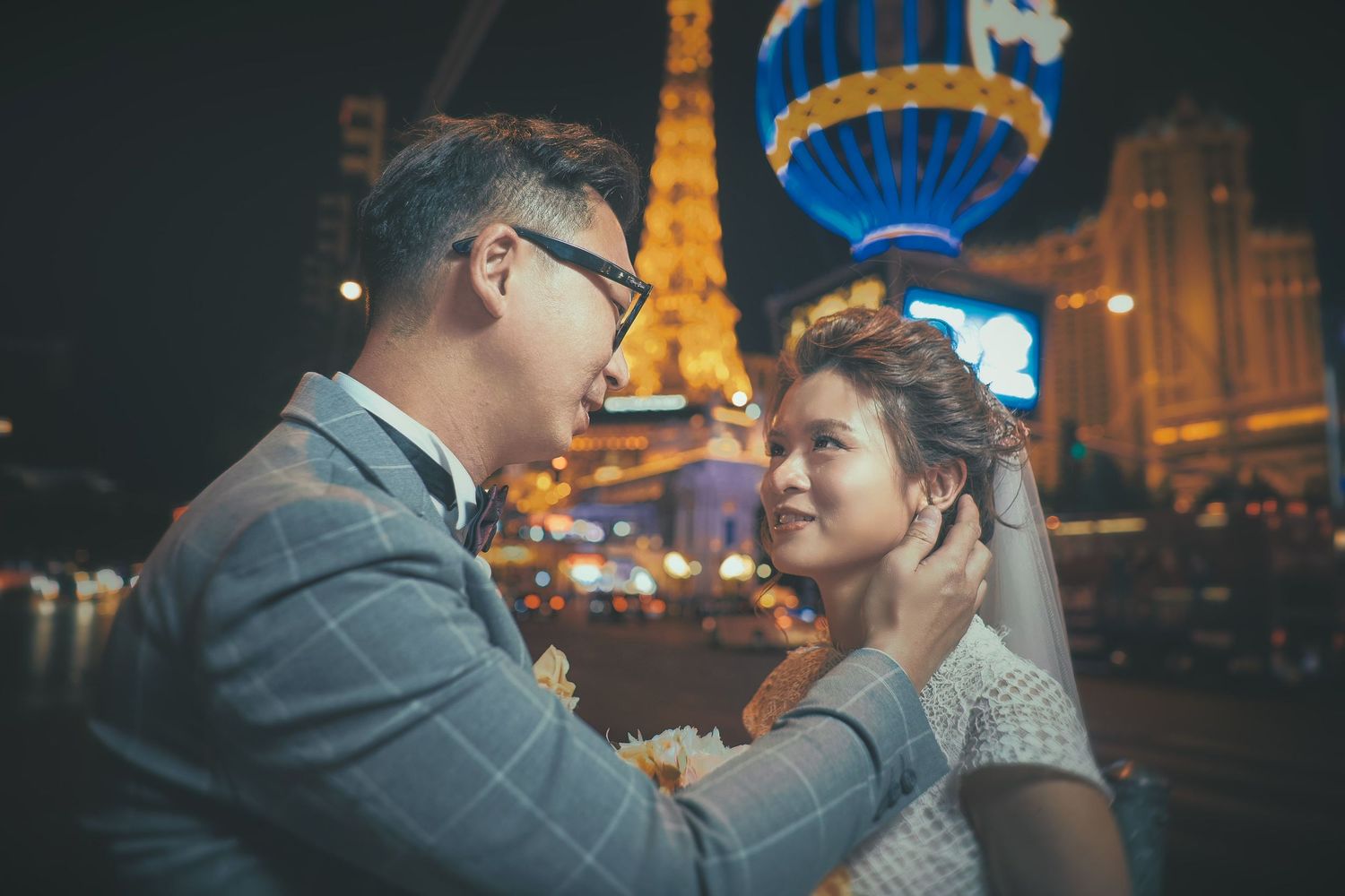 Couple sharing a romantic moment at night with the Las Vegas Strip Eiffel Tower replica glowing in the background.