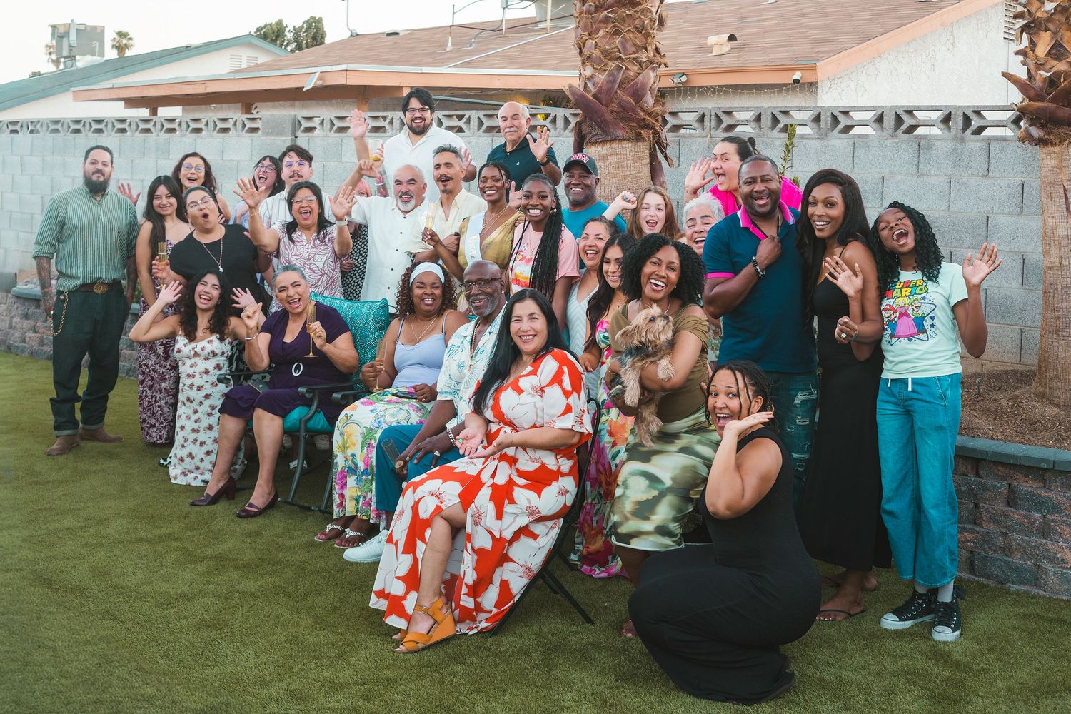 Large diverse group of people smiling and posing together outdoors in a backyard during a celebration.