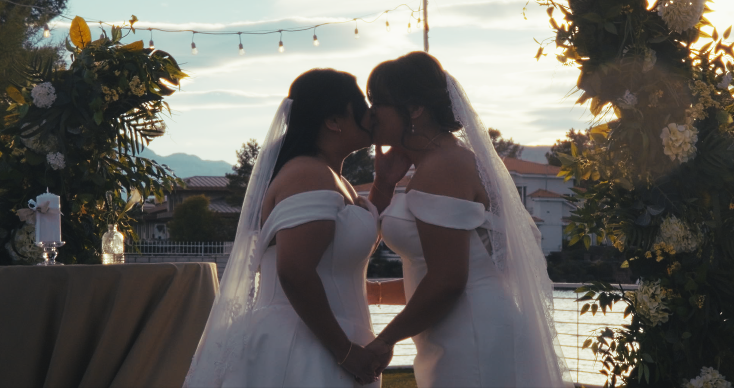 Two brides holding hands and sharing an intimate moment at sunset ceremony.