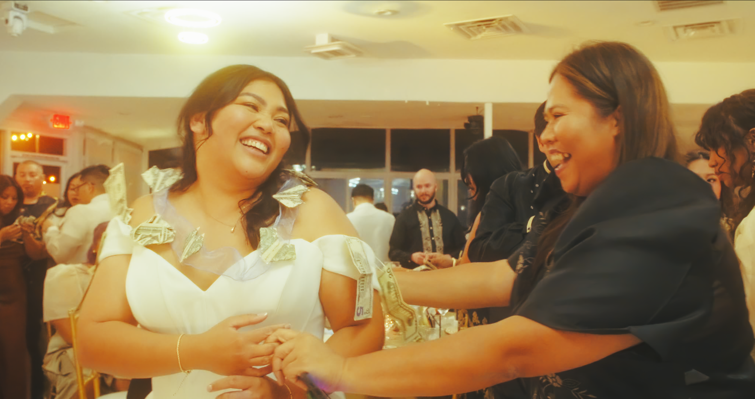 Two women laughing and dancing joyfully at a wedding reception celebration.
