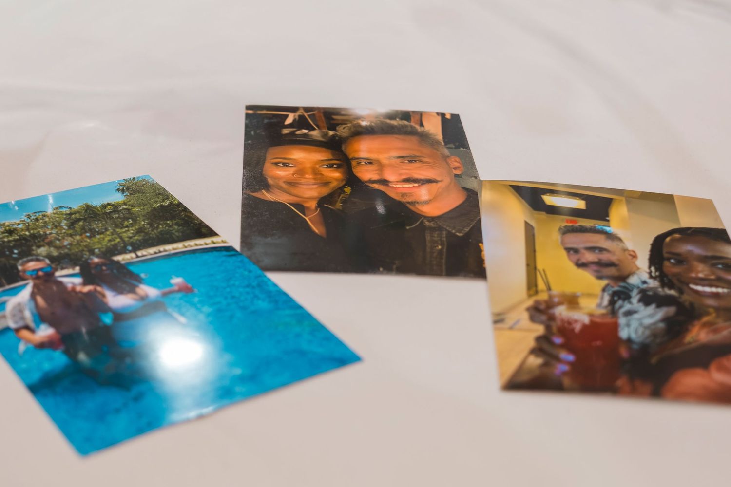 Three printed photos of friends and family laid on a white surface, showing candid moments and selfies.