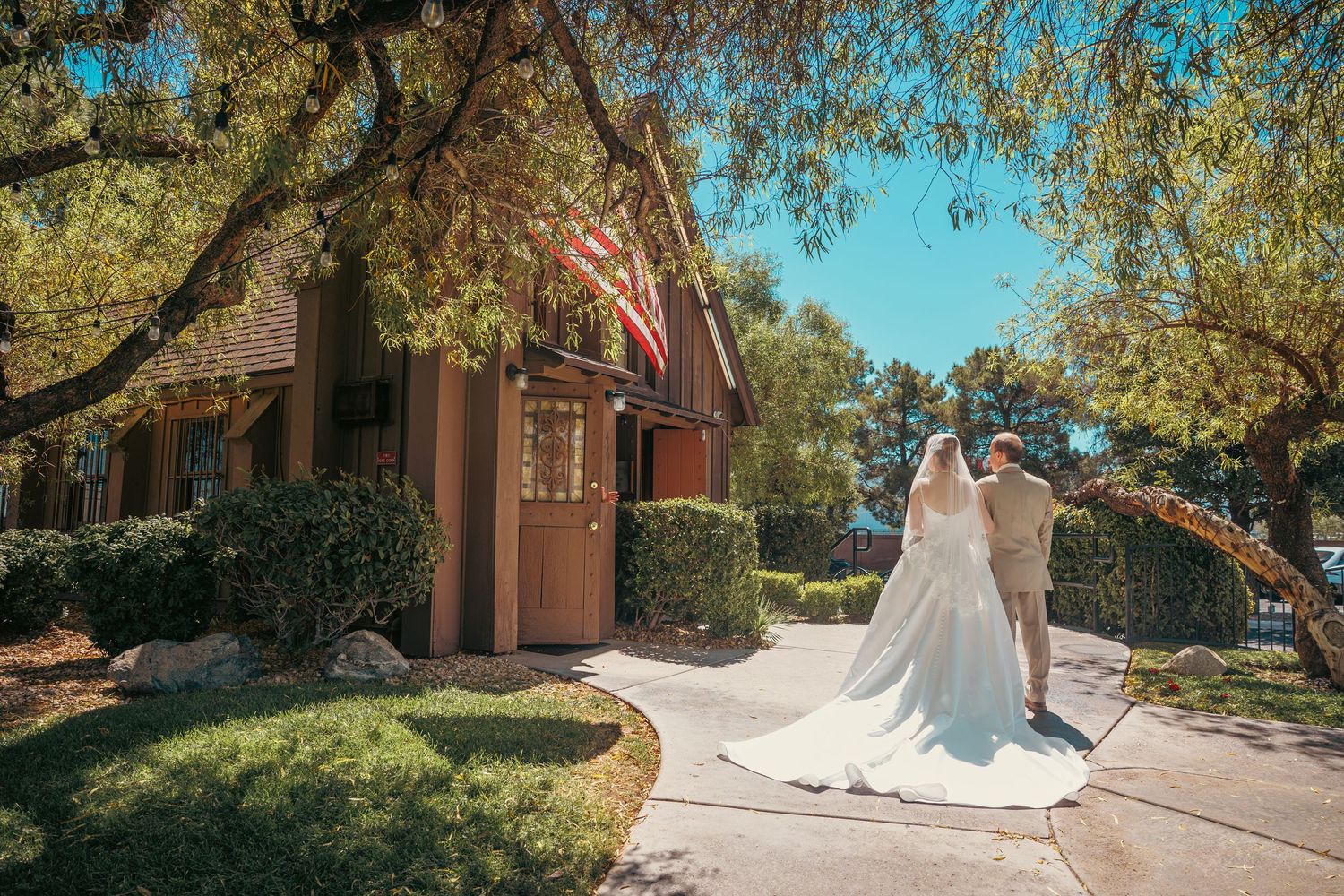 Bride and groom walking hand in hand outside a charming chapel with an American flag in Las Vegas.