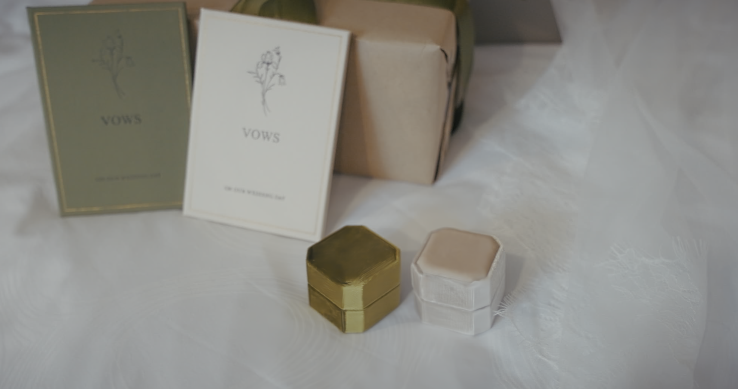 Two small ring boxes with floral cards displayed on a white surface.