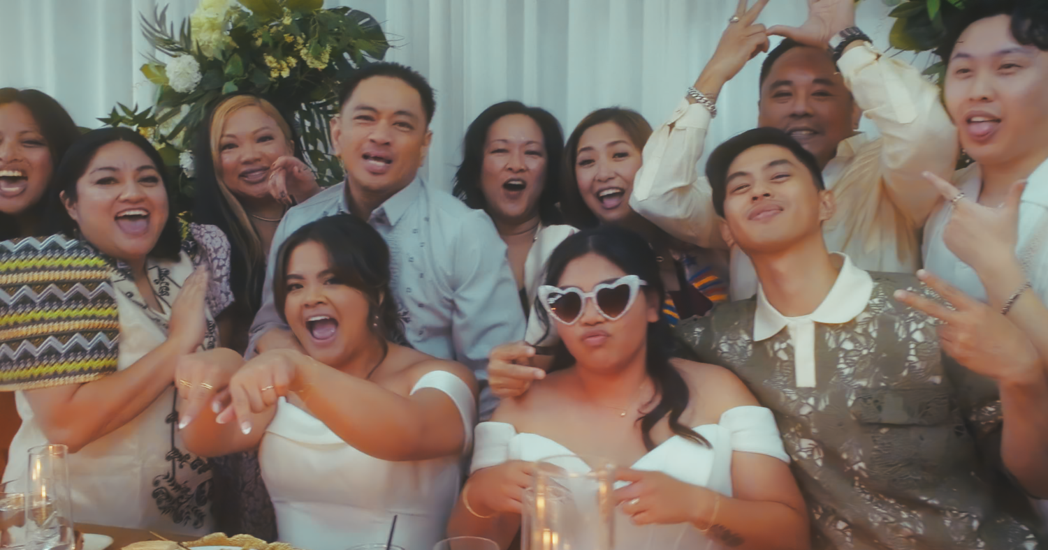 Large group of happy wedding guests posing together at a festive reception table.
