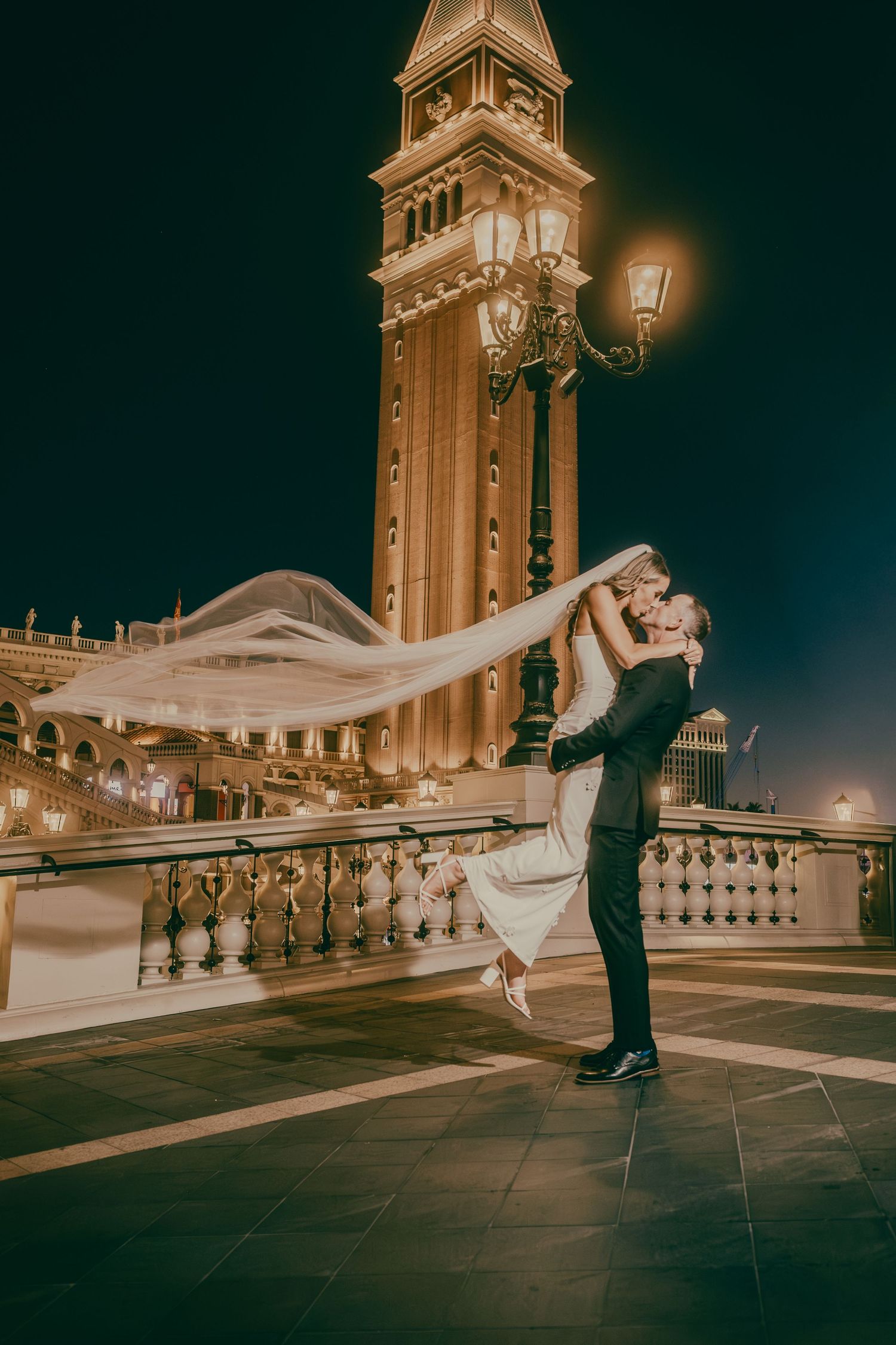 Romantic night photo of groom lifting bride with cathedral veil at The Venetian Las Vegas.