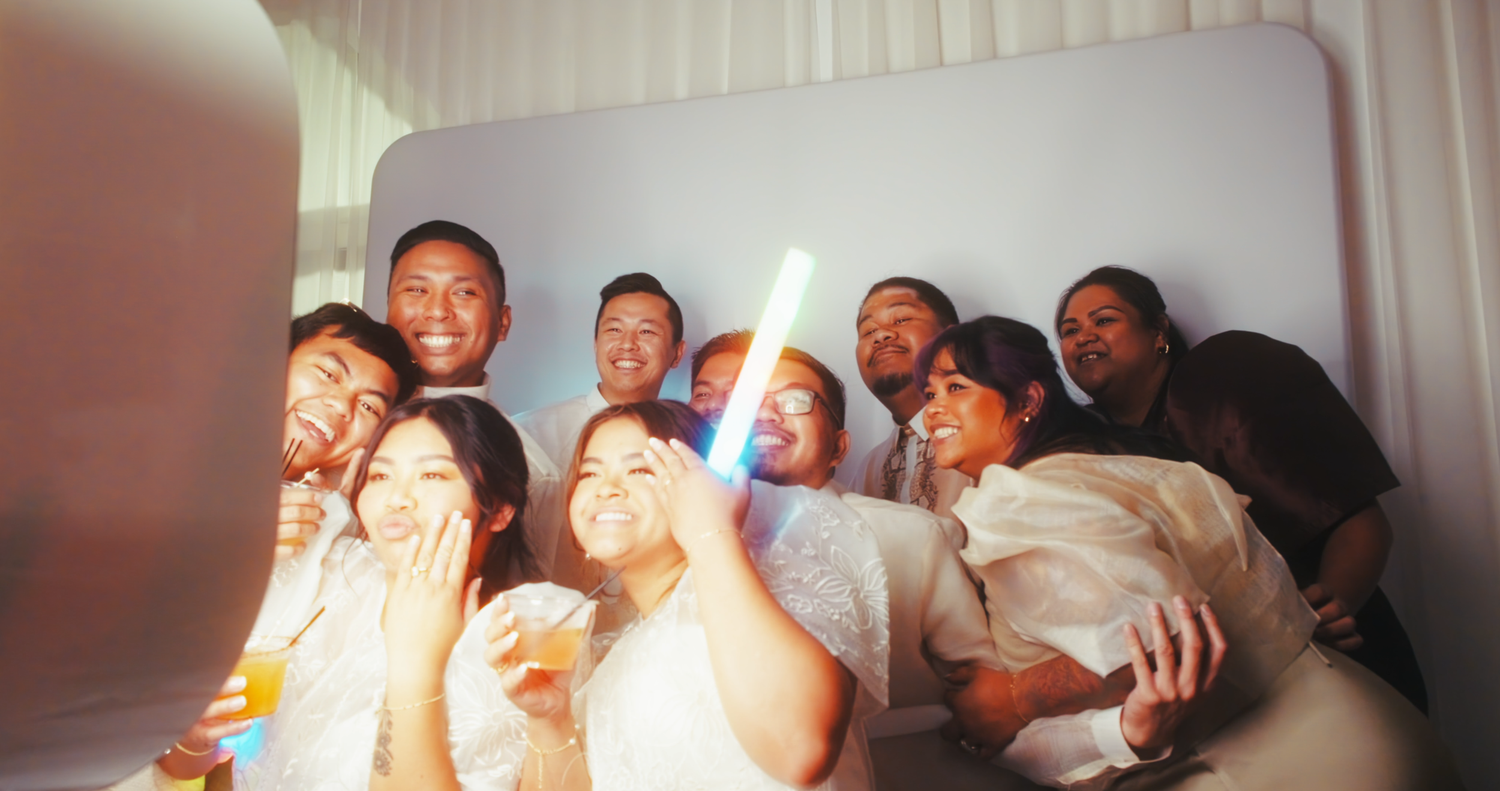 Group of friends taking a fun selfie together at a wedding reception photo booth.