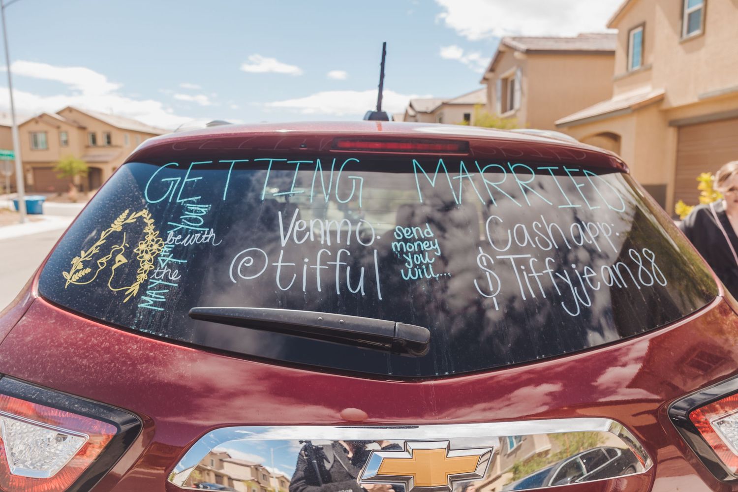 Red SUV rear window decorated with wedding messages and Venmo payment details for newlyweds.