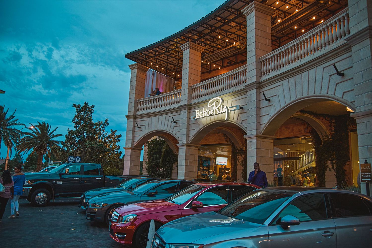 Exterior of BabaRu restaurant at dusk with luxury cars parked outside a colonial-style building with warm lights.