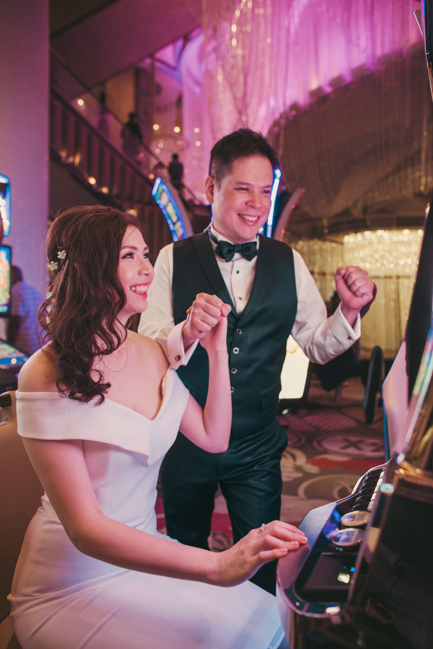 Excited bride and groom celebrating at a slot machine inside a glamorous Las Vegas casino during wedding shoot.